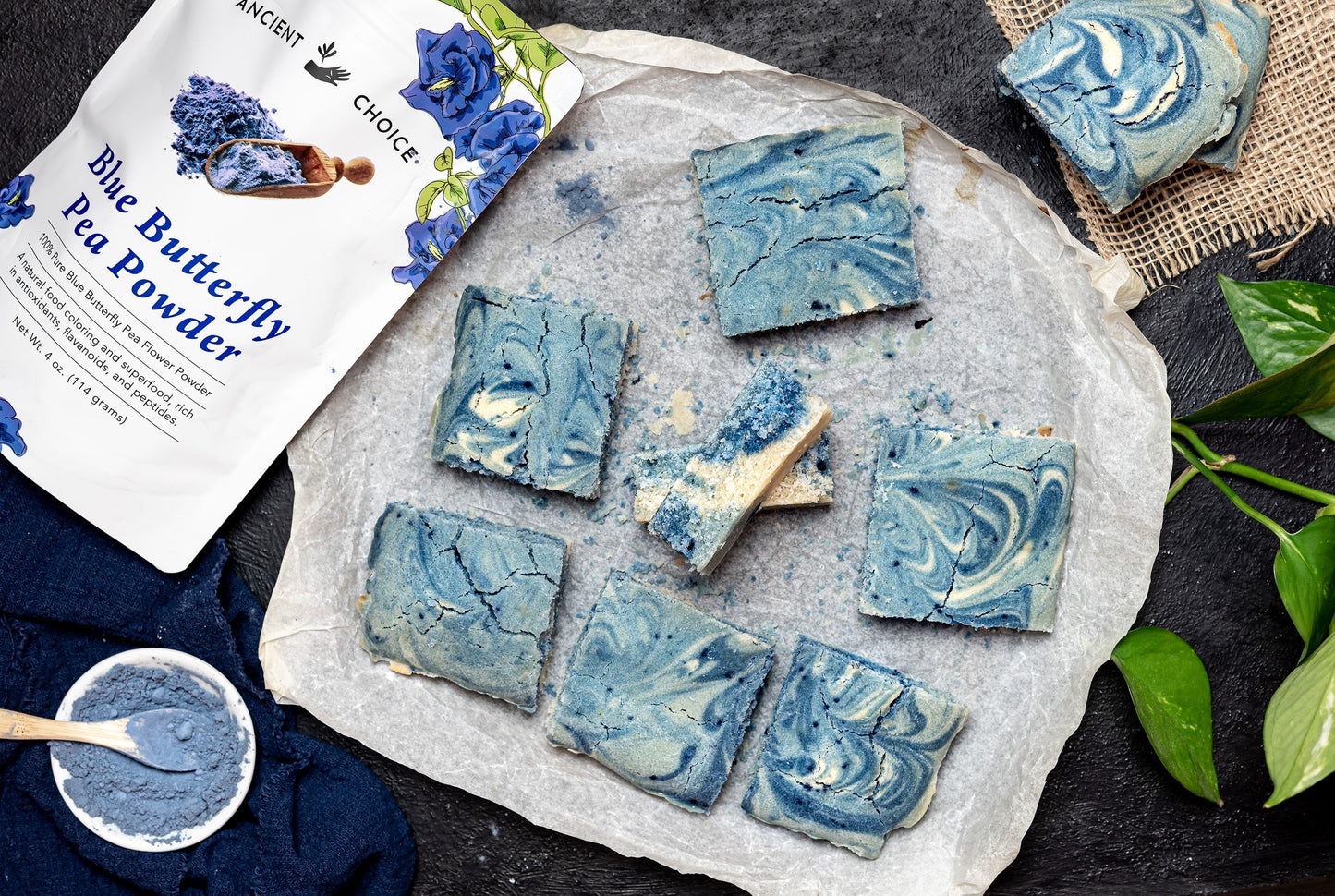 An array of blue swirl cake pieces sitting beside a bowl of butterfly pea flower powder